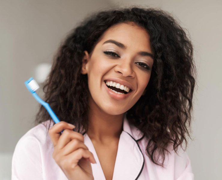 lady-sitting-on-bed-with-toothbrush-in-hand-and-M2E86QA-1.jpg